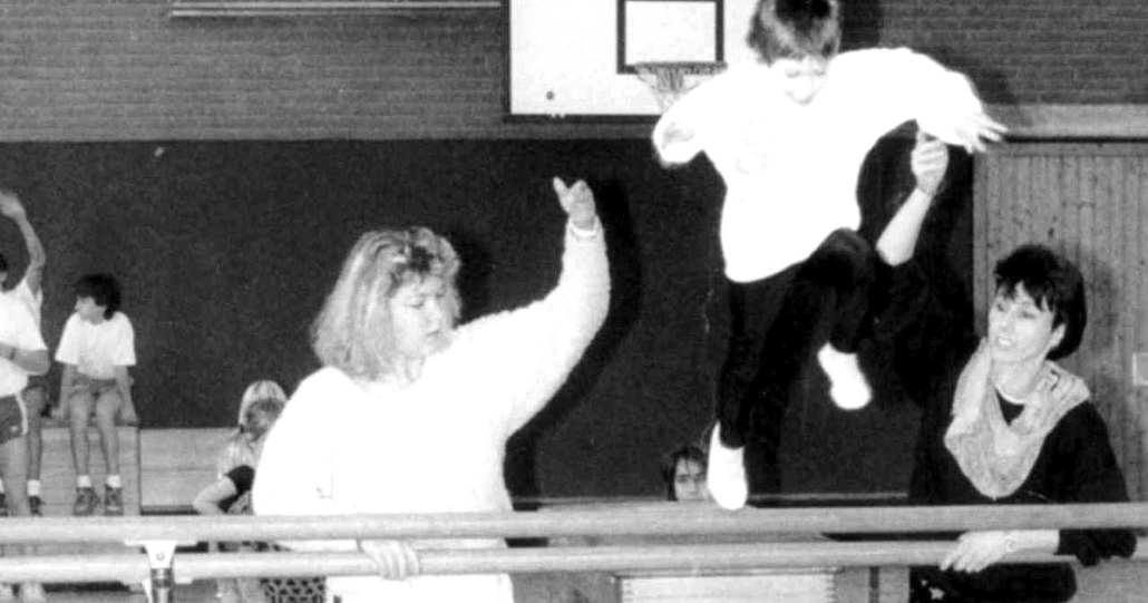 Beim Kinderturnen: Zwei Frauen helfen einem Kind beim SPrung über einen Kasten.